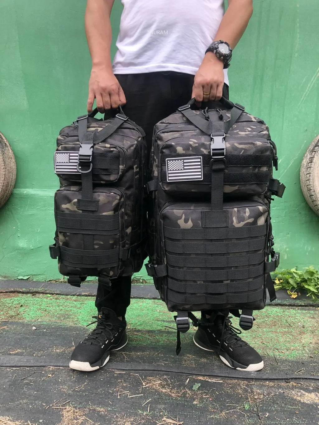 Tactical MOLLE rucksack pair in dark camouflage, front flap pockets and U.S. flag patch
