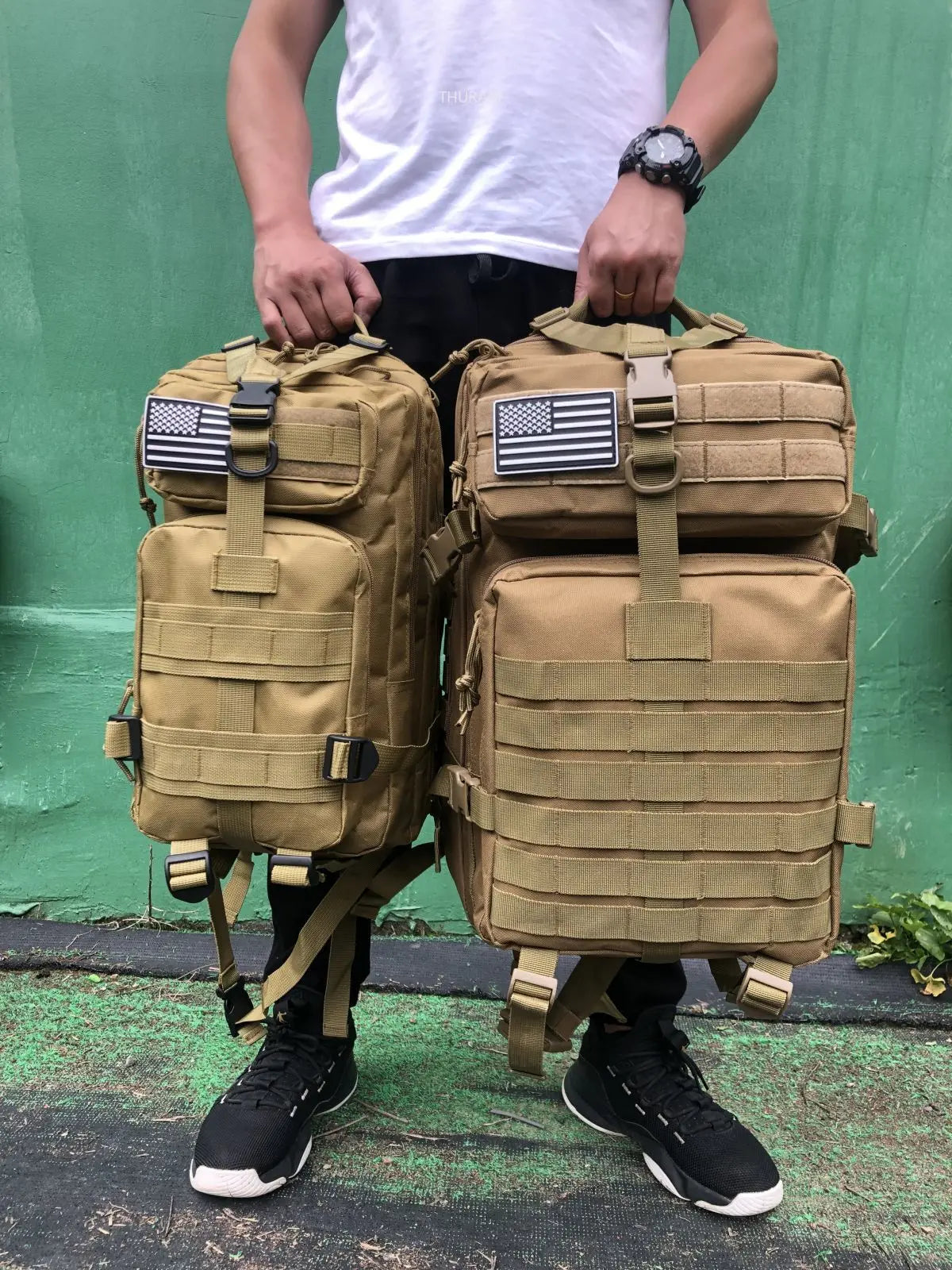 Tactical MOLLE rucksack pair in tan with front flap pockets, webbing straps, U.S. flag patches