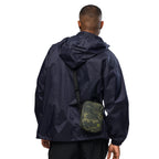 Digital camo crossbody bag on wearer’s back with black strap and flap pocket