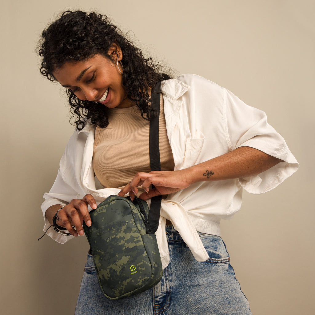 Digital camo crossbody bag worn over shoulder with black strap and front zipper pocket.