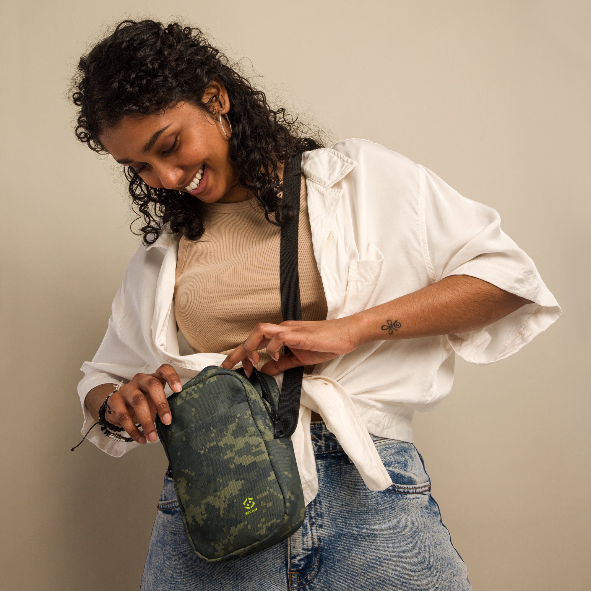 Digital camo crossbody bag worn over shoulder with black strap and front zipper pocket.