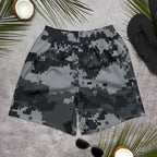 Digital camo athletic long shorts with elastic waistband, flat lay on a gray surface