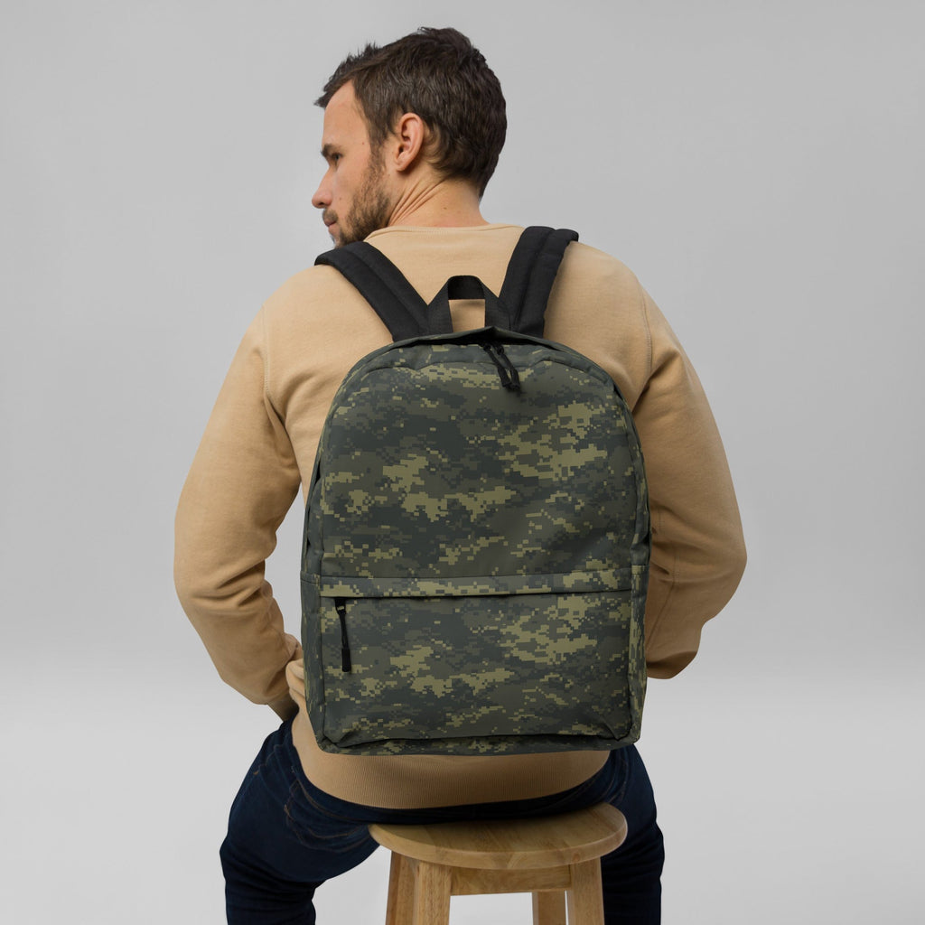 Camouflage backpack worn on back with top handle and front zipper pocket.