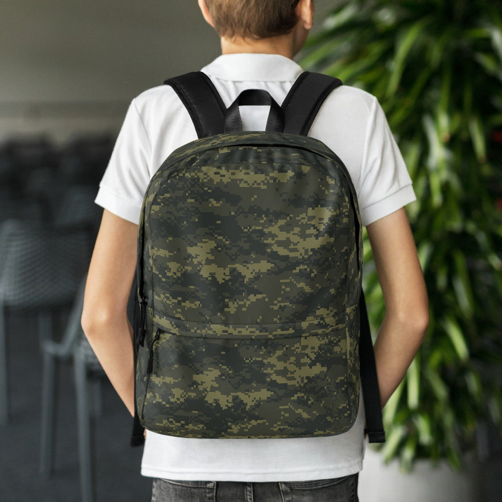 Digital camouflage backpack worn on back, with top handle and front zipper pocket.