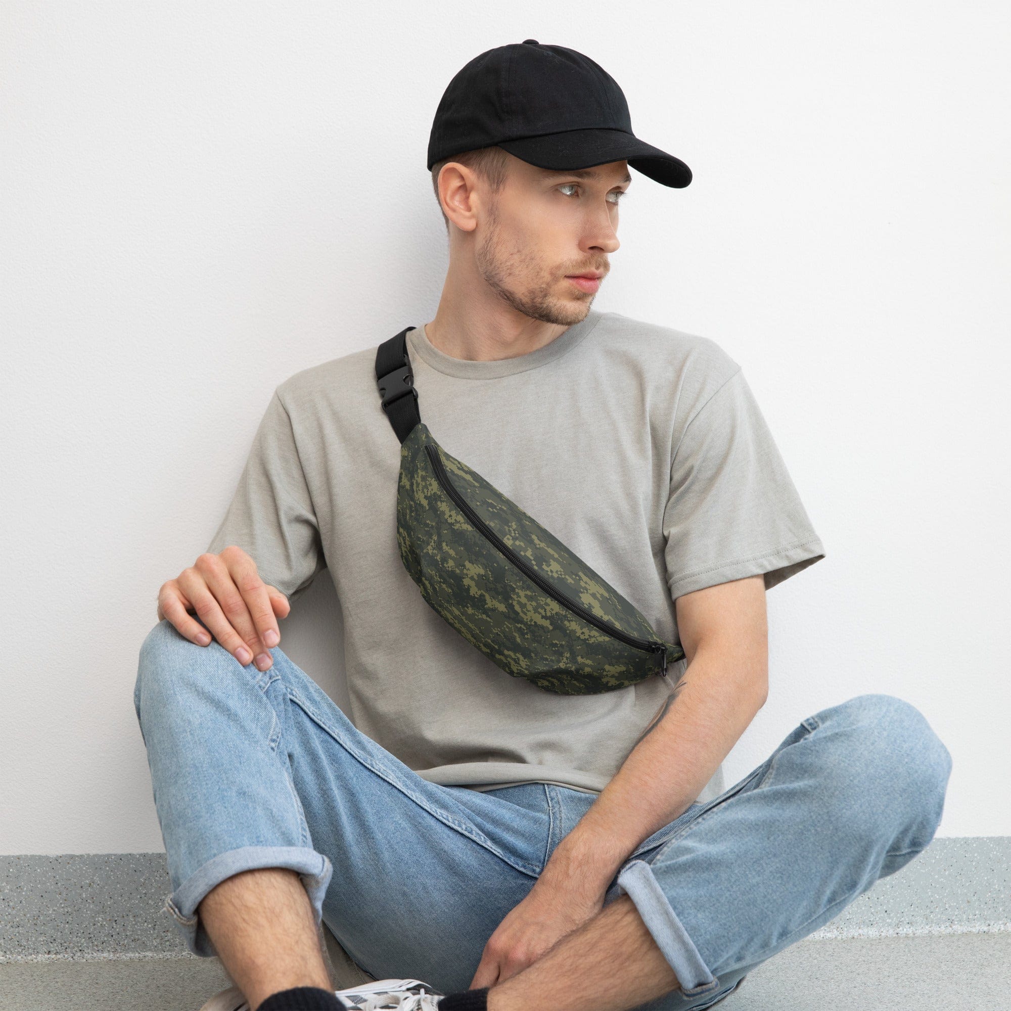 Camouflage waist bag worn across chest with black strap and zippered pocket