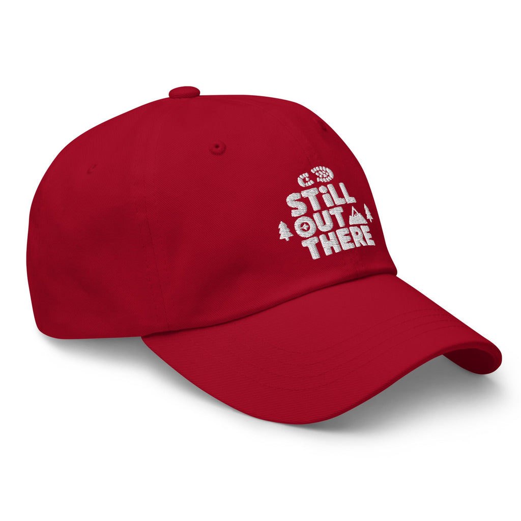 Red dad hat with white embroidered “Still Out There” logo on the side