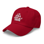 Red dad hat with white embroidered “Still Out There” logo on the front panel