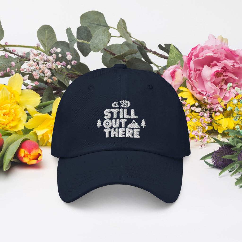 Navy dad hat with embroidered “STILL OUT THERE” logo on front and curved brim.