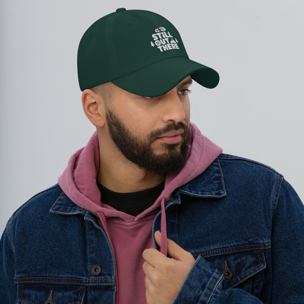 Green dad hat with embroidered “STILL OUT THERE” logo on front and curved brim.