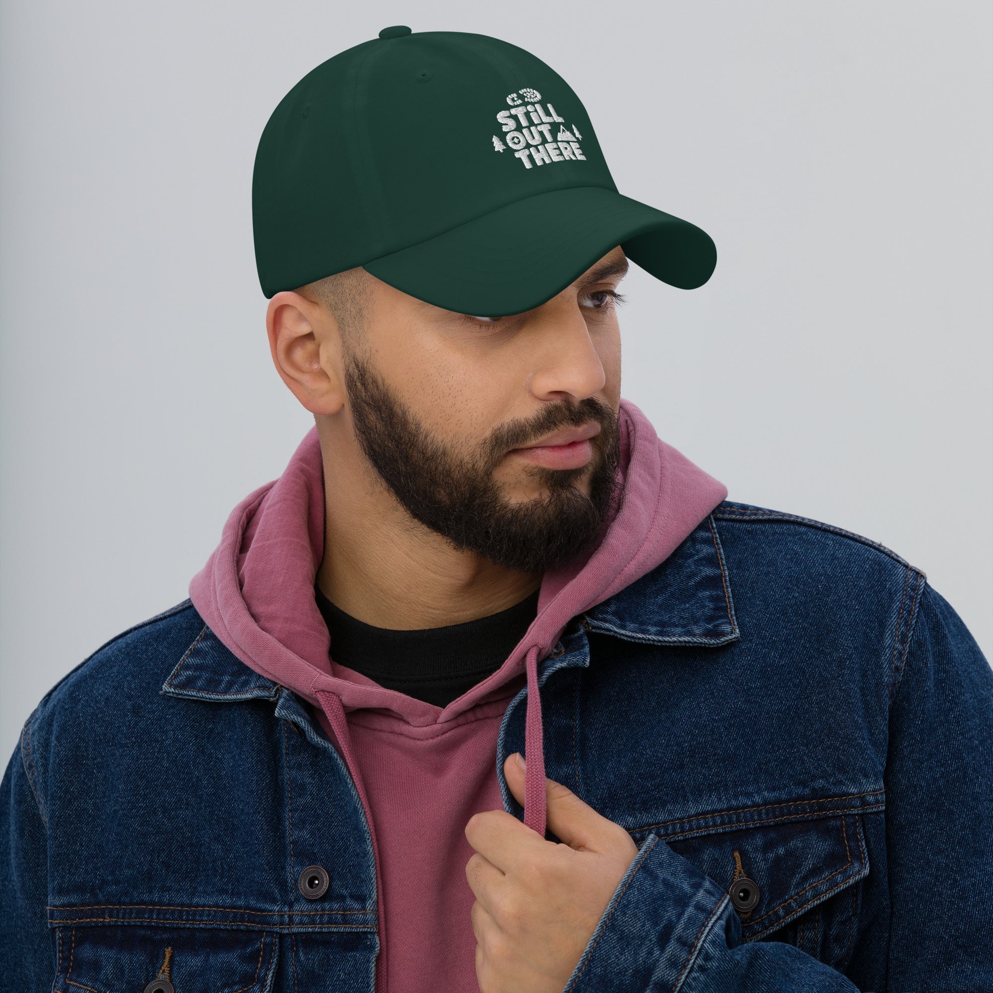 Green dad hat with embroidered “STILL OUT THERE” logo on front and curved brim.
