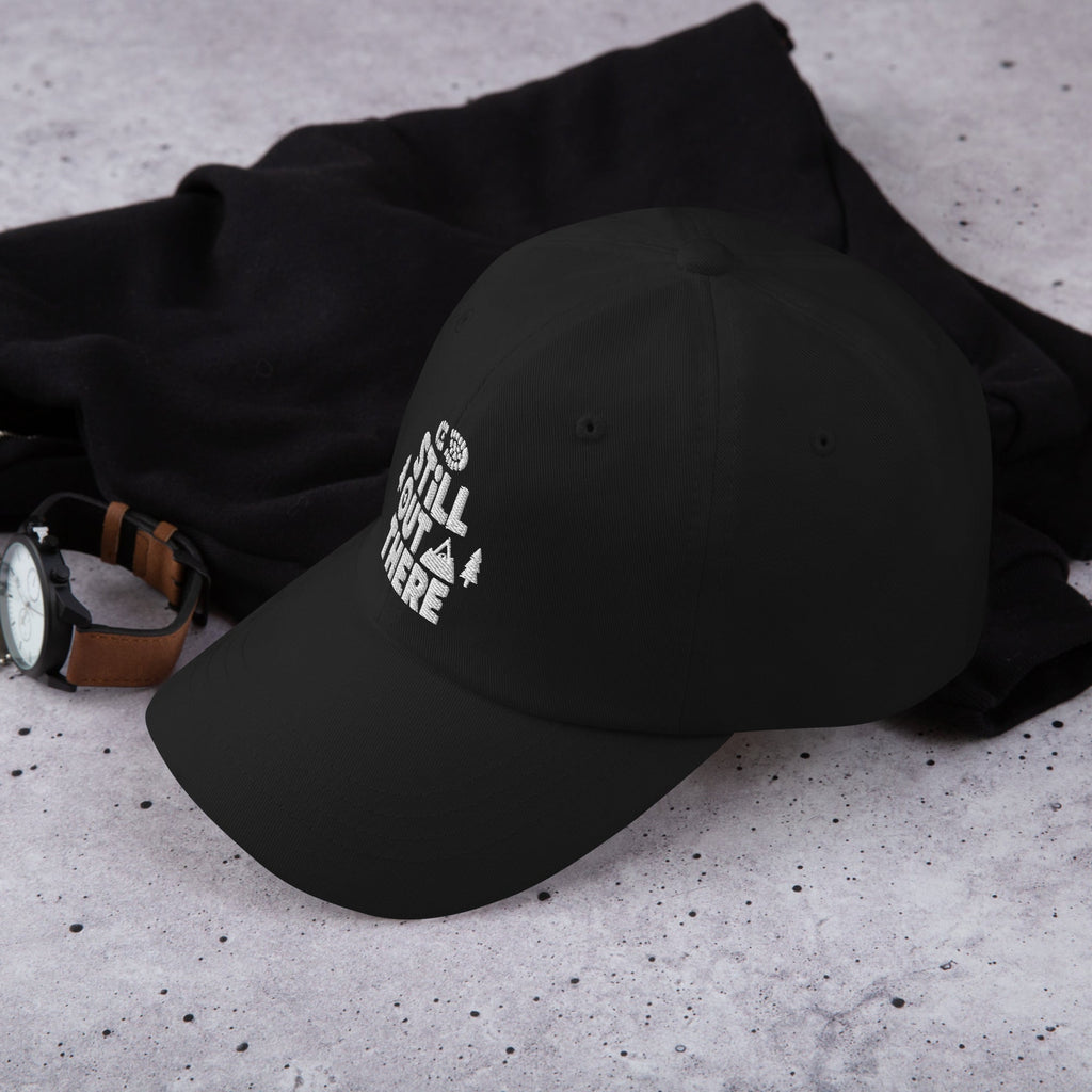 Black adjustable dad hat with white embroidered “Still Out There” logo on the front