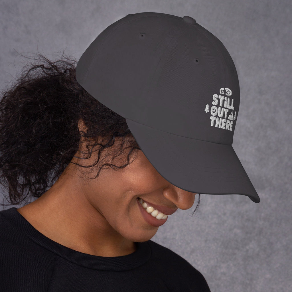Gray baseball cap with embroidered “STILL OUT THERE” logo on front and curved brim.