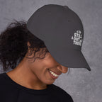 Gray baseball cap with embroidered “STILL OUT THERE” logo on front and curved brim.