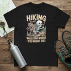 Black hiking T-shirt with skull-and-forest front graphic and text 'Walking where you might die'