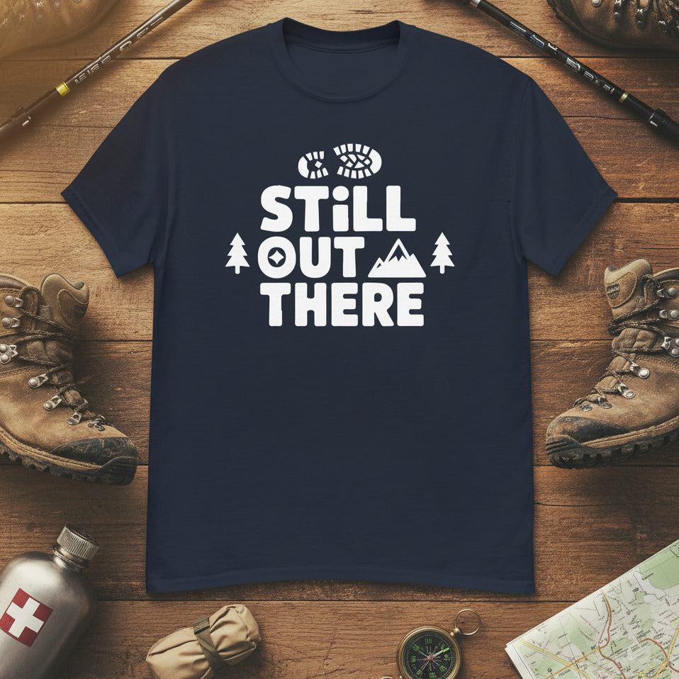 Navy hiking T-shirt with white “STILL OUT THERE” logo and trees graphic