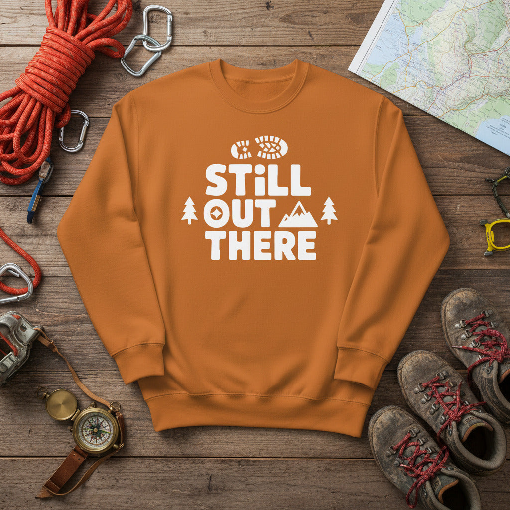 Hiking premium sweatshirt, tan with white "STILL OUT THERE" logo and tree graphic